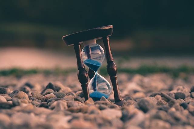 An hourglass sitting on top of a pile of rocks.